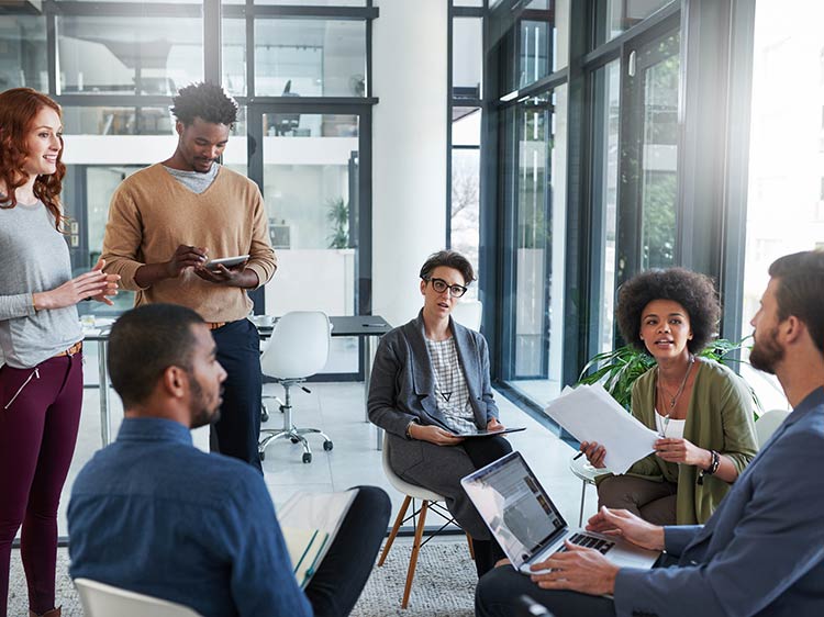 A diverse team collaborating happily in an office, representing a successful outcome of hiring for cultural fit.